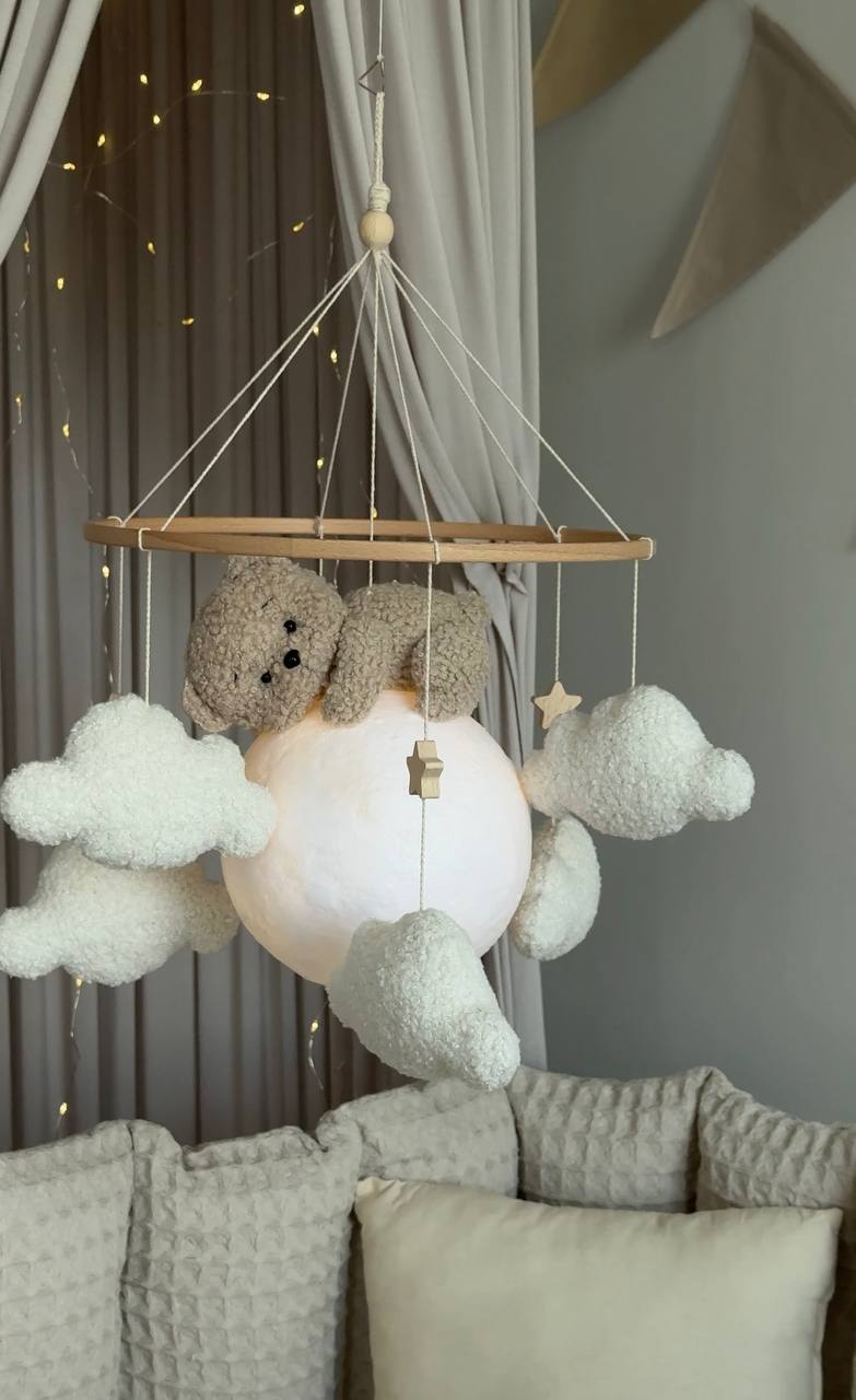Children's room with a hanging mobile featuring clouds and a teddy bear.