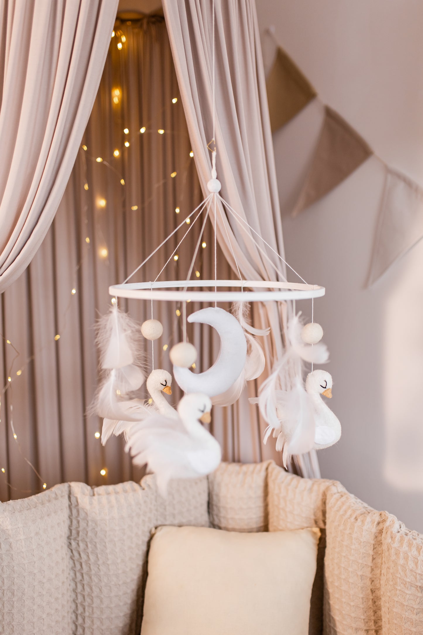 Decorative mobile with swan figures hanging above a sofa in a softly lit room.