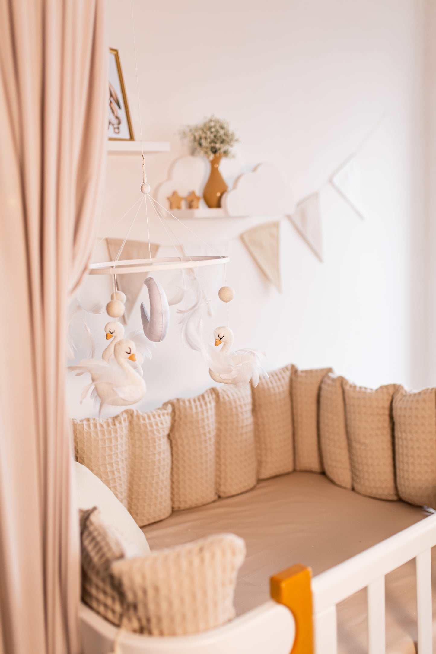 Nursery room with a crib, swan baby mobile, decorative pillows, and wall art.