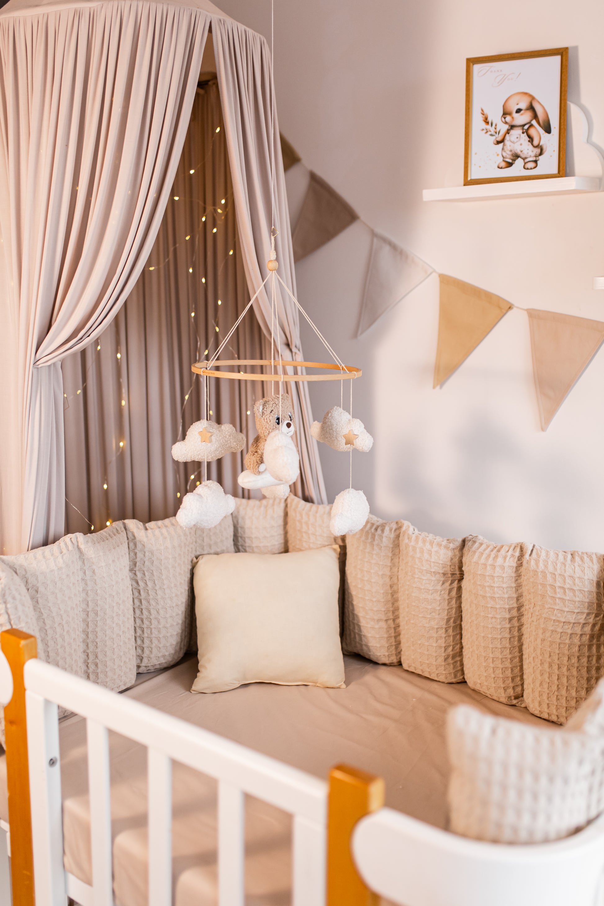 Children's room with a crib, decorative pillows, and a hanging baby mobile.