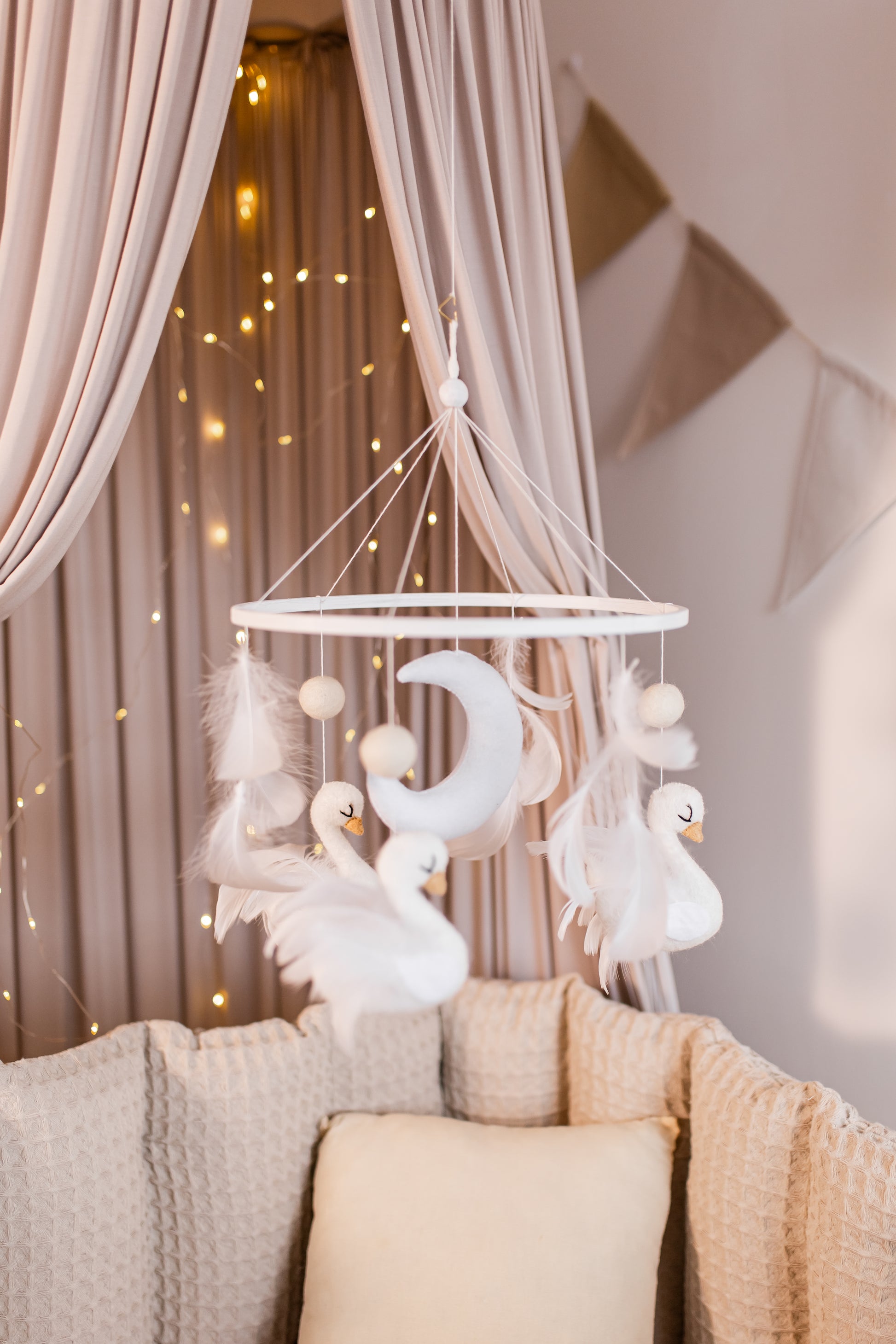 Decorative mobile with swan figures hanging above a sofa in a softly lit room.