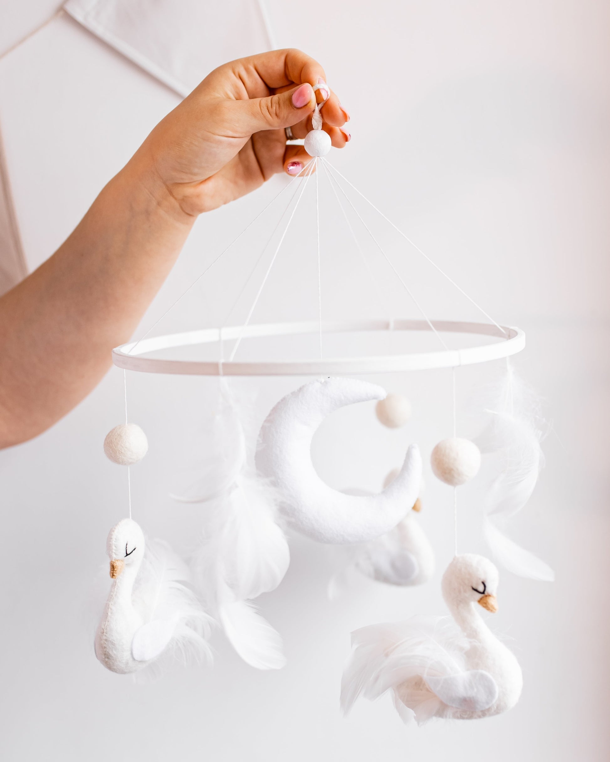Boucle swan baby mobile hanging above crib in gentle tones